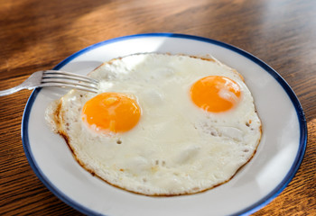 Two fried eggs like a smiley face on the tray with the light blue platter