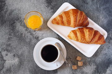 Two fresh croissants, orange juice and cup of coffee for breakfast. Top view