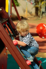 Cute baby boy climbing rope net or ladder