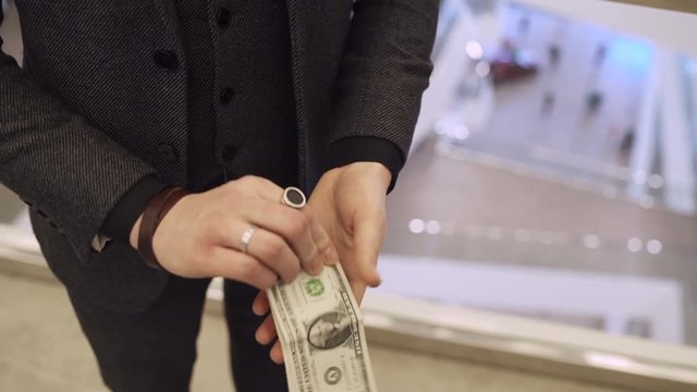 Magician showing money trick, hands closeup. Trick with dollars. illusionist. The man in a suit, interior on background. Currency.
