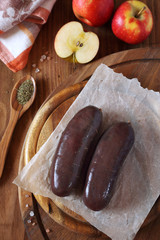 Raw blood sausage with apples on wooden chopping board. Top view