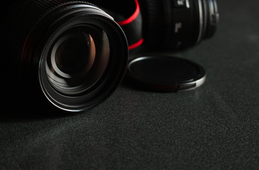 closeup digital camera on black wooden table with soft-focus in the background. dark color tone and over light