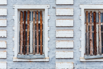 Part of the facade of the old brick building with boarded up windows.