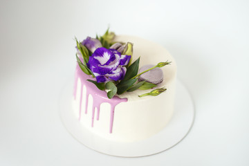 White wedding cake with purple flower detail on white background