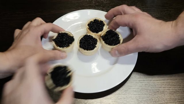On the table is a plate of canapes of black caviar