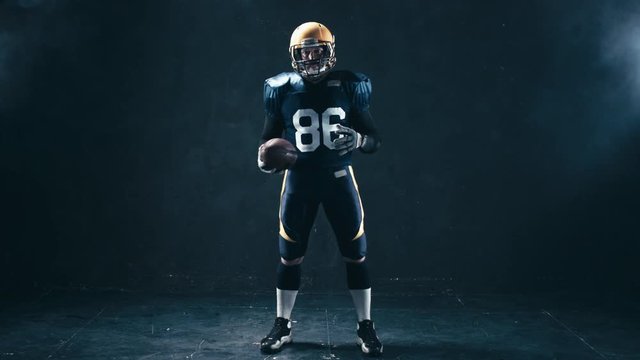 Full portrait of Caucasian male American football player holding a ball and pointing into camera. 4K UHD RAW edited footage