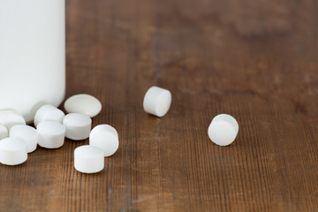 White Round Pills by a Medicine Bottle