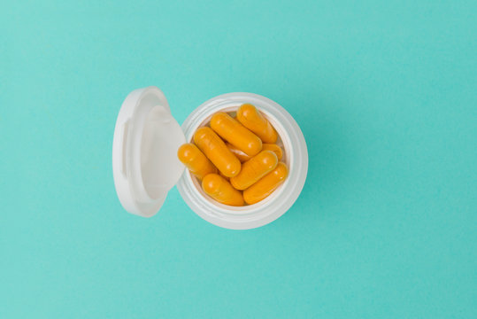 Overhead Of Opened Bottle Filled With Orange-Colored Capsules