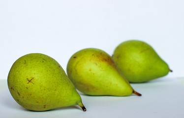 three pear lie next to, three pears on white background, green pears, the fruits are arranged in a row, three pears