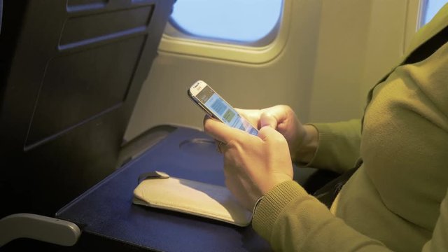 High quality video of woman using cell phone in the airplane in 4K