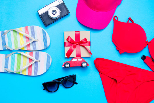 beautiful swimsuit, sunglasses, car shaped toy, camera, gift, cap and sandals on the wonderful blue background