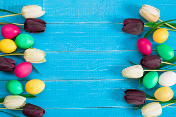 colorful easter eggs and bouquet of tulips on wooden background with space for a text © nazarovsergey