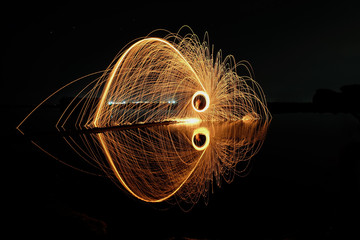 Firework showers of hot glowing sparks from spinning steel wool on the ground. Light painting  (Long Exposure)
