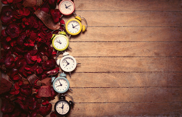 colorful alarm clocks and romantic dried flower petals on the wonderful brown wooden background