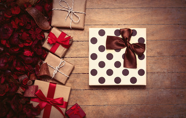 gifts of different sizes and romantic dried flower petals on the wonderful brown wooden background