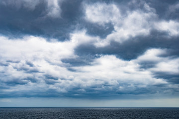 Naklejka na ściany i meble Atlantic Ocean with dramatic blue sky and clouds behind cruiser