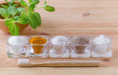 alternative natural toothpaste xylitol or soda, turmeric - curcuma, himalayan salt, clay or ash, coconut oil and wood toothbrush, mint on wooden