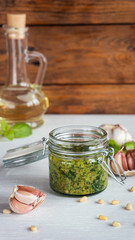 Glass jar of pesto sauce on white kitchen table.