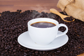 Coffee cup and beans on wooden background