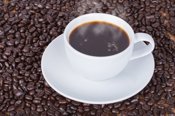 Coffee cup and beans on wooden background