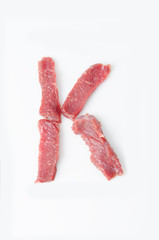 The letter K Latin alphabet of red beef meat on a white background