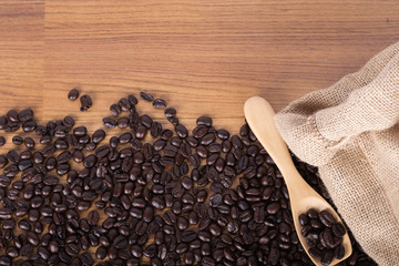 coffee beans on wooden spoon with burlap on table background