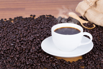 Coffee cup and beans on wooden background
