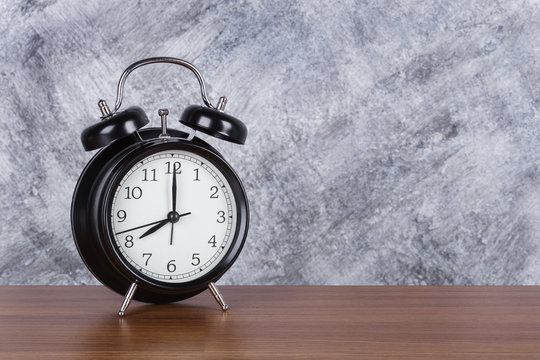 8 o'clock vintage clock on wood table and wall background