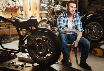 Fototapeta na wymiar Stylish man sitting between motorbikes