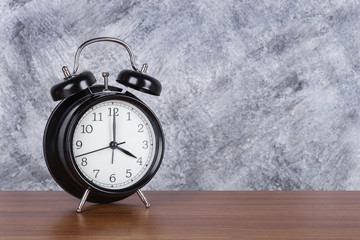 4 o'clock vintage clock on wood table and wall background