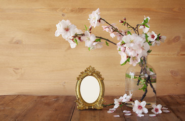 Vintage blank photo frame next to spring flowers