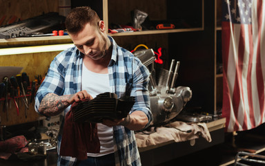 Handsome serious man cleaning spare part