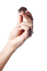 Hand holding a traditional candy from Brazil called brigadeiro over white background
