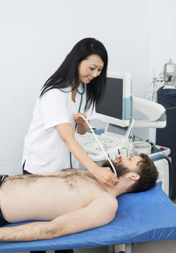 Doctor Performing Thyroid Ultrasound Test On Patient