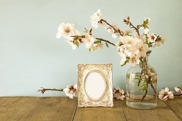 Obraz premium Vintage blank photo frame next to spring flowers