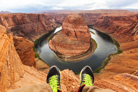 Legs of traveler man sitting on the background of the canyon Horseshoe bend, Arizona, USA. Travel concept, scenic view