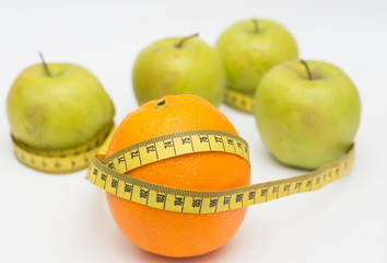 orange and green apple with a measuring tape on a white background