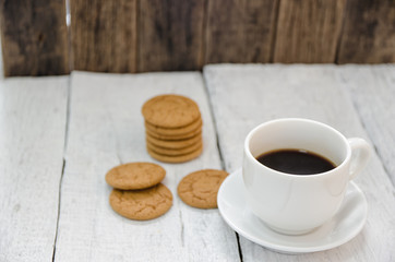 Coffee and cookie on wooden white table.