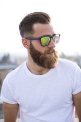 Bearded man posing in the street with sunglasses.