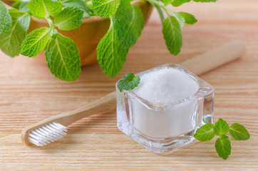 alternative natural toothpaste xylitol, soda, salt, and wood toothbrush closeup, mint on wooden