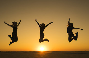 Fototapeta na wymiar Three sporty funny happy woman are jumping in the air at sunset time