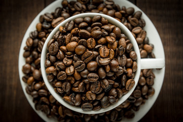 Coffee beans in the cup on dark wooden background