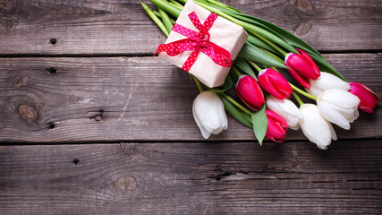 Box with gift  and bright  spring  tulips flowers on rustic wooden background.