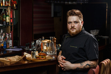 Chef in black uniform presenting a tray with burger