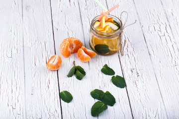 Bowl with slices of orange and mint leaf stands on white table