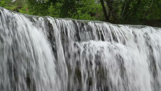 Seamlessly looping video footage features water pouring over the edge of an Upper Cataract Falls, a waterfall in rural Owen County, Indiana.