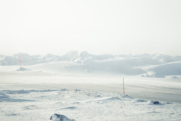Fototapeta na wymiar A beautiful landscape with a white, snowy road with safety poles in the Norwegian winter