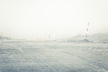 A beautiful landscape with a white, snowy road with safety poles in the Norwegian winter