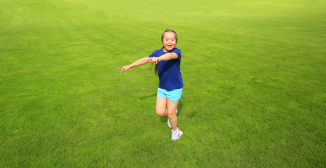 Little girl running on green grass background