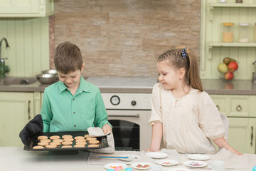 Fototapeta premium Cute kids baked cookies and tasting it at the table in the home kitchen